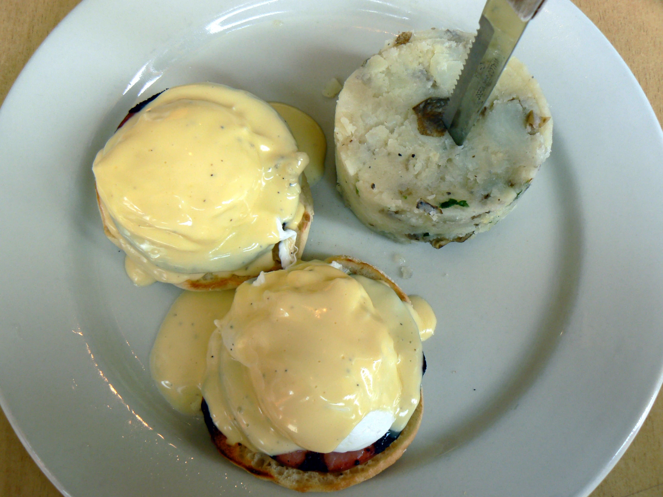 a white plate topped with two eggs benedicts and rolls