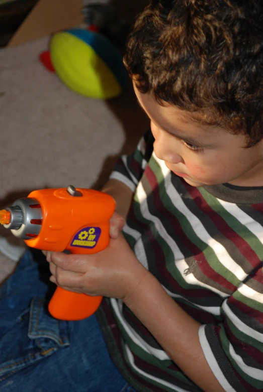 a  holds an orange toy blow up gun