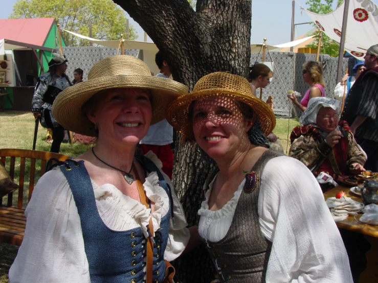 two women in period clothing standing under a tree