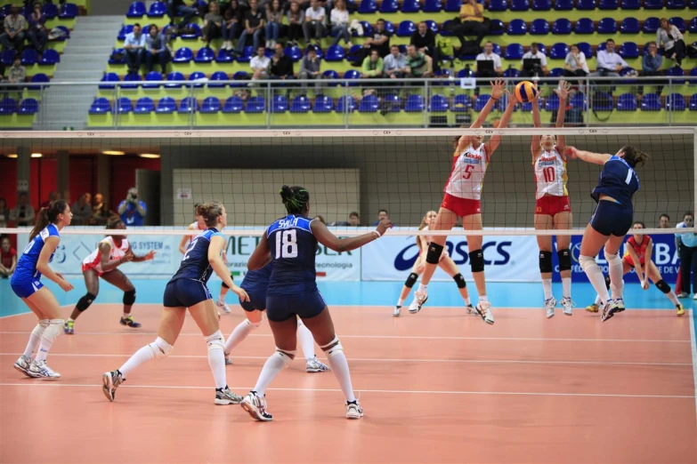 a group of women in sports uniforms playing volleyball