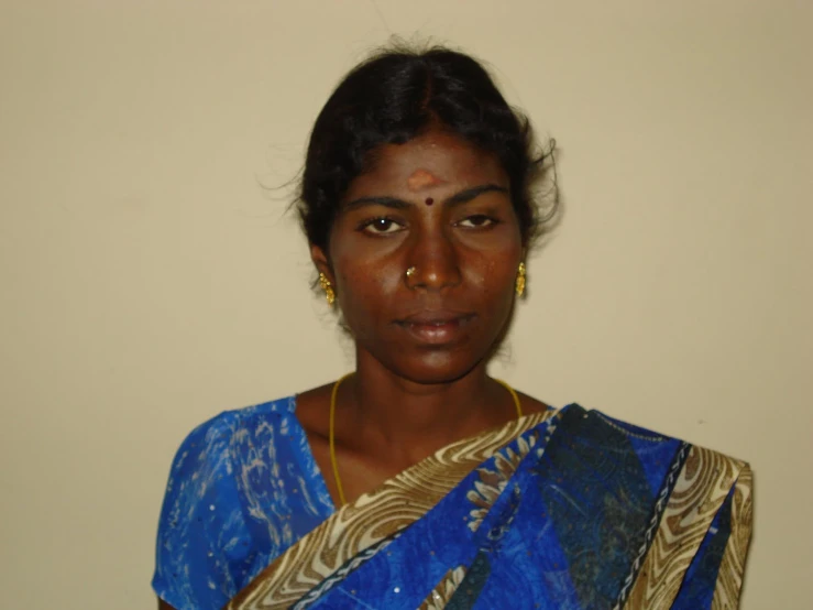 a woman with dark skin and brown hair wearing blue dress