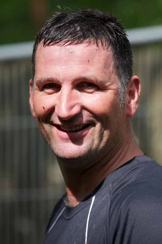 a man in a black shirt smiles at the camera