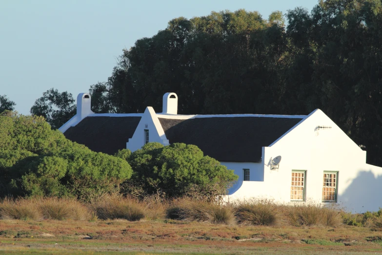 a large white house with a black roof near some trees