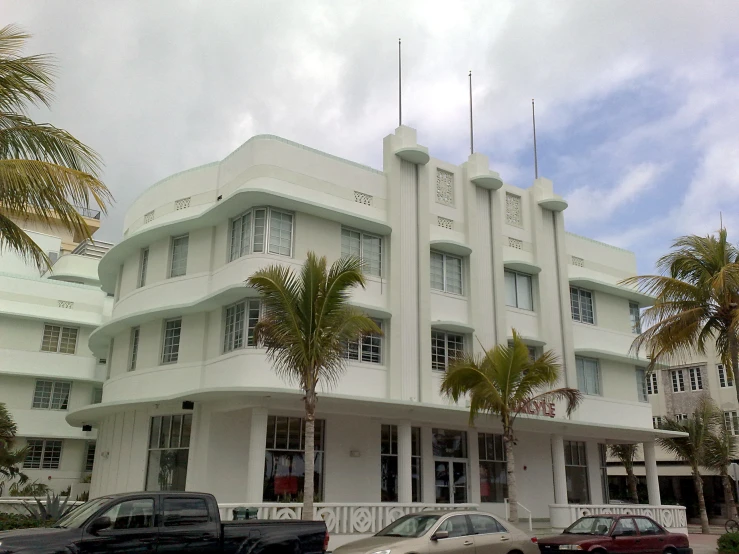 a very tall white building in front of several palm trees