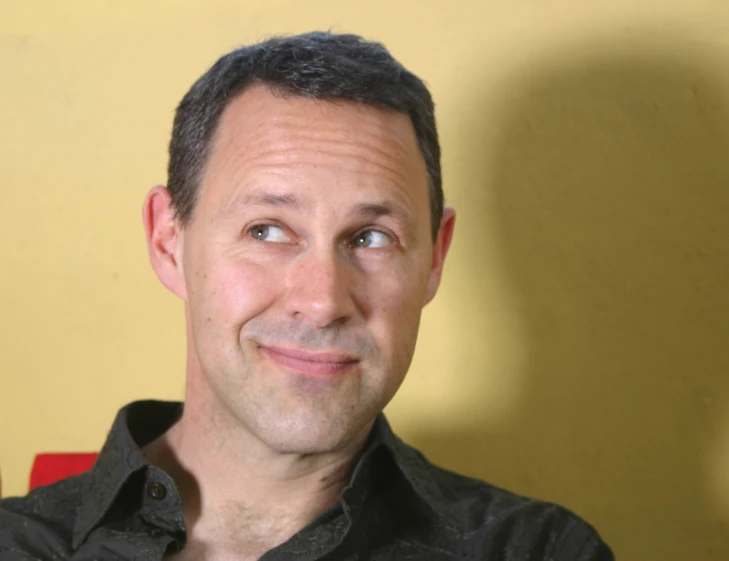 a man in a black shirt with his hand under his chin