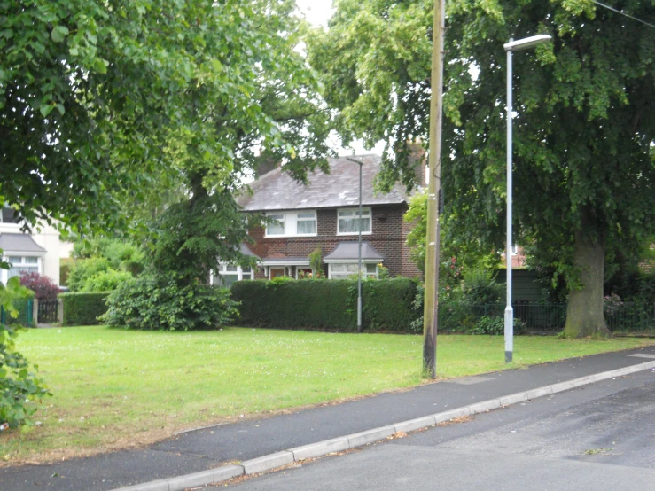 an empty road with trees and a car parked at the curb