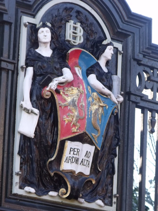 an ornate metal sign shows that the design is of three women with books