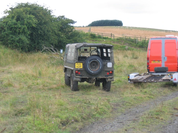 an suv is parked beside a red van on the grass