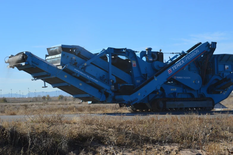 a large blue truck moving over a rural field