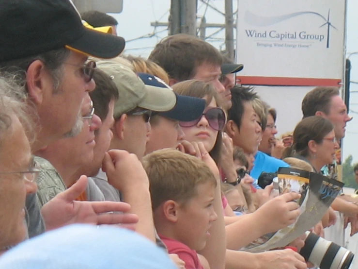 many people look into an old po camera as they sit and watch the action on tv