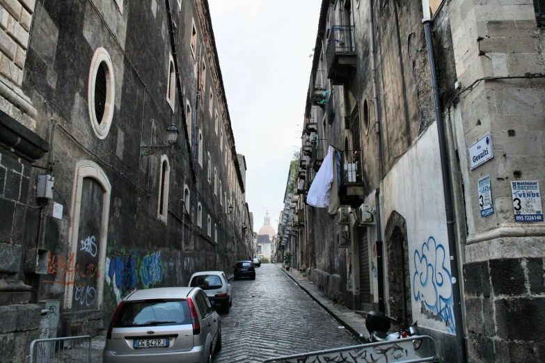 cars parked on a narrow street between buildings