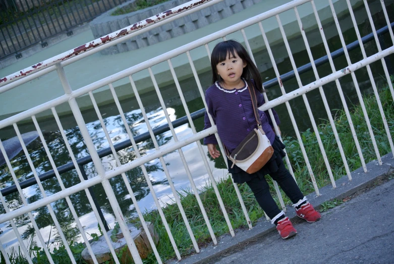 a young child standing by a railing with a bag