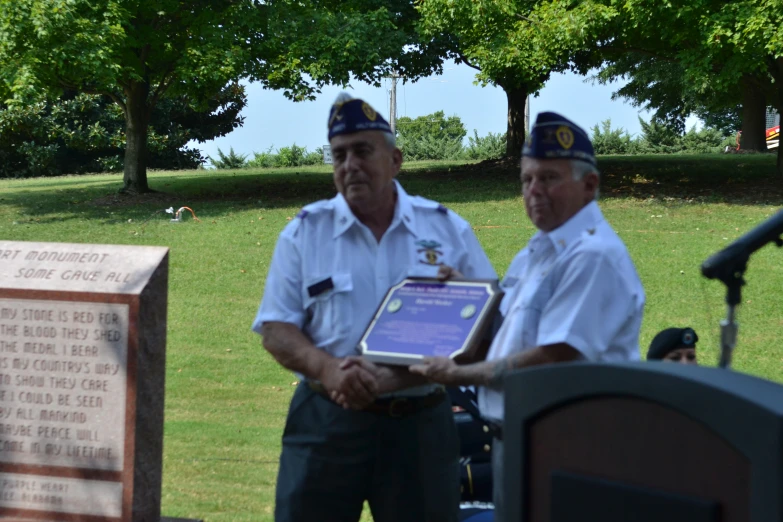two men standing next to each other holding a plaque