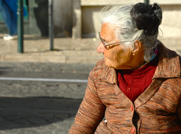 an old woman in a brown coat is walking down the street