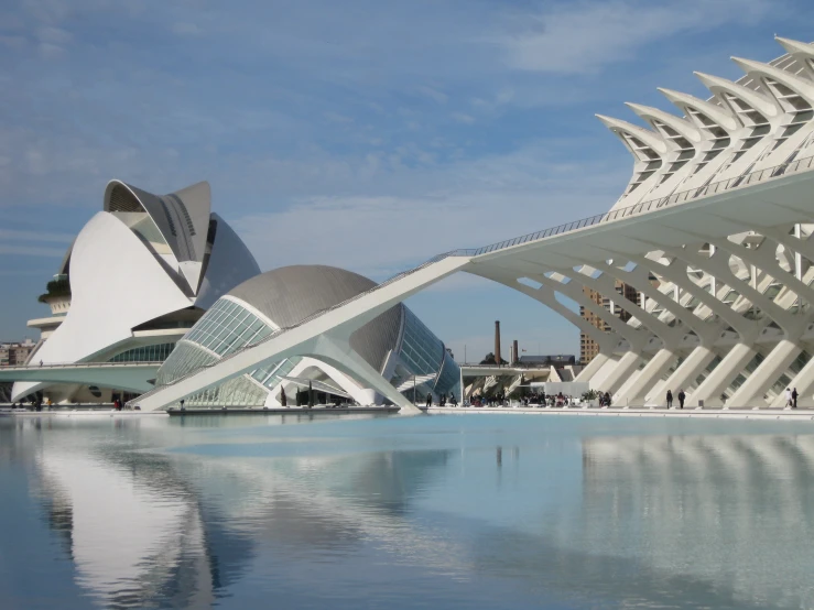 large artistic structure sits on a water pool surrounded by buildings