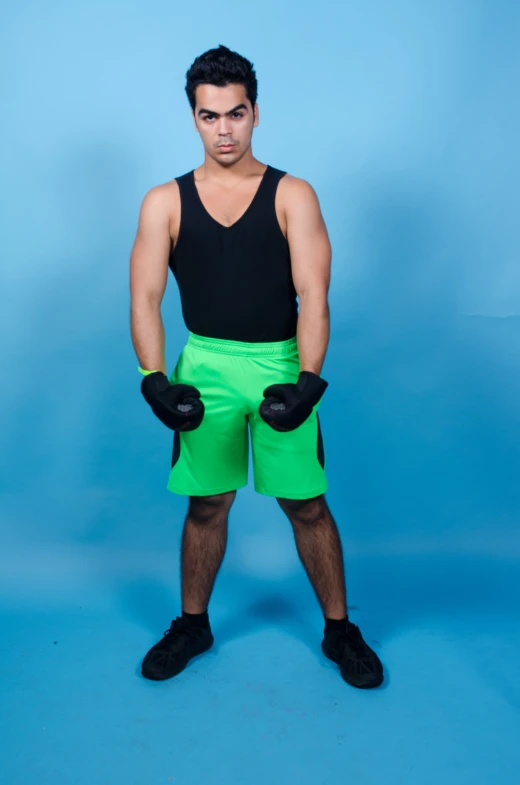 a young man in black shirt and neon green shorts posing