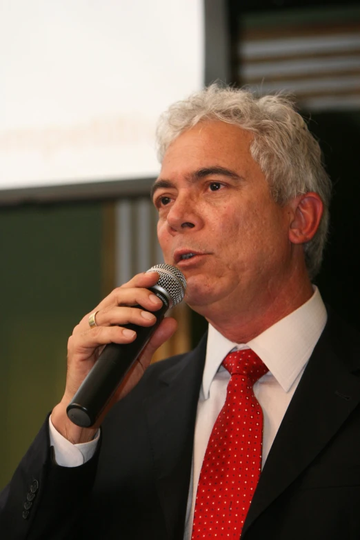 a man with grey hair is speaking into a microphone