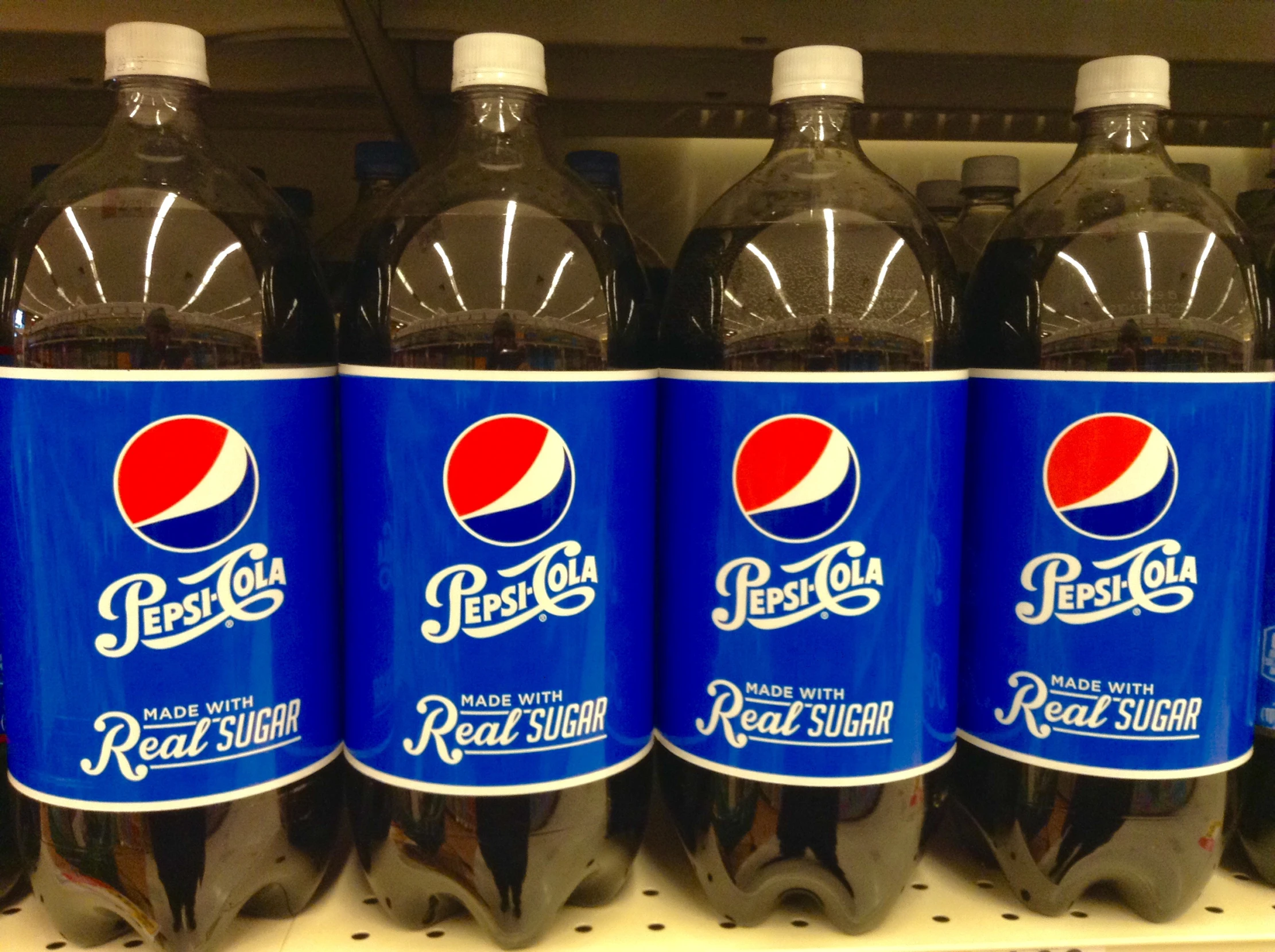 three pepsi cola bottles are on the shelf