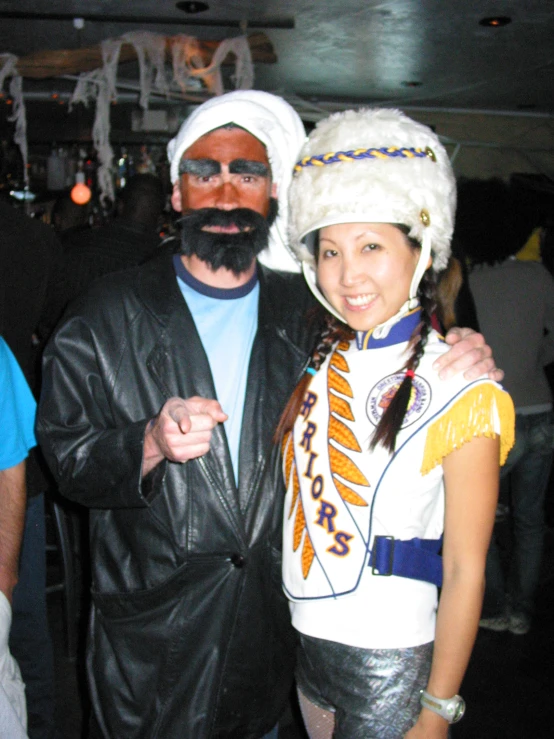 a woman in leather pants and white hat standing next to a man