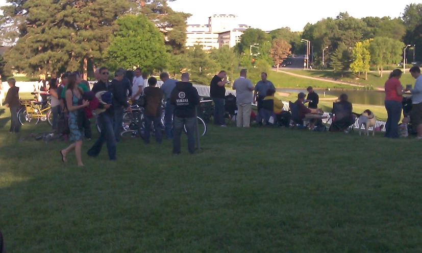 several people standing in a park next to a pond