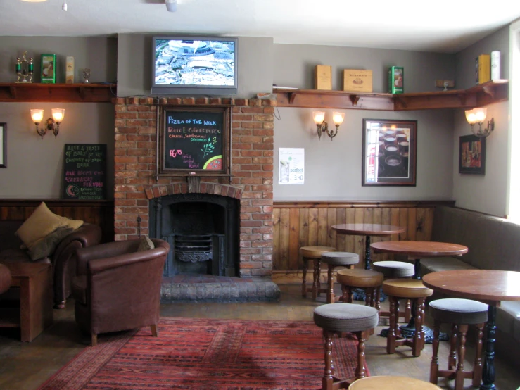 a brick fireplace in a coffee shop that has lots of tables around it