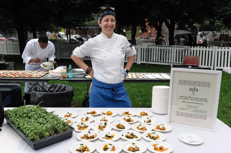 woman wearing blue and white uniform standing next to many plates of food