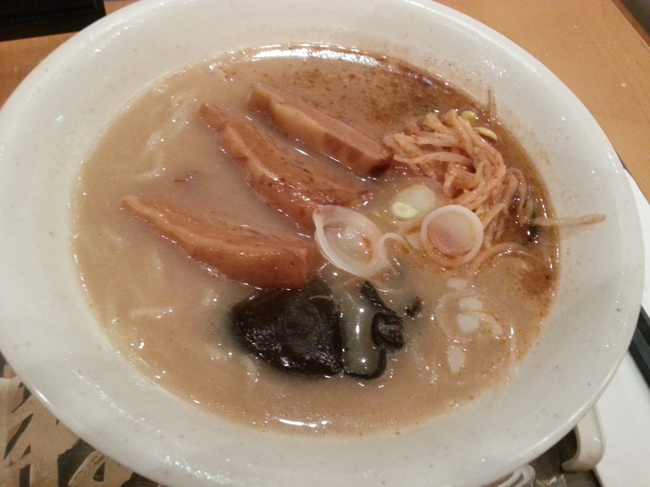 a white bowl containing soup with meat, rice and other ingredients