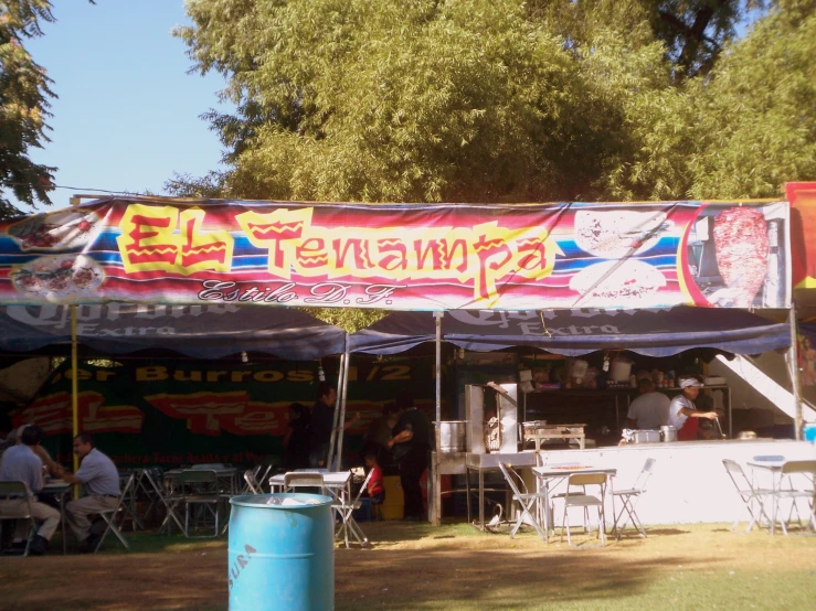 a tent with a large sign above it and tables under it