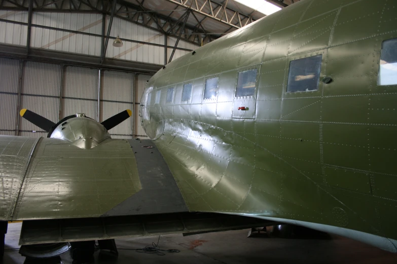 an army green plane parked in a building