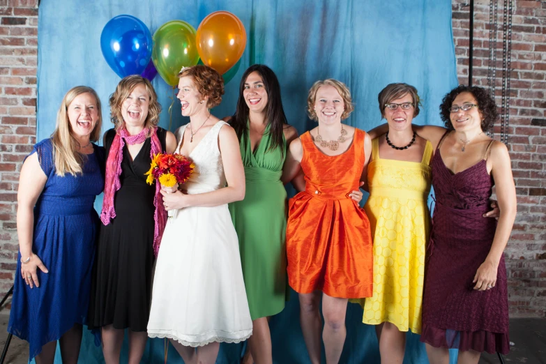 six woman dressed in colorful dresses posing for a po