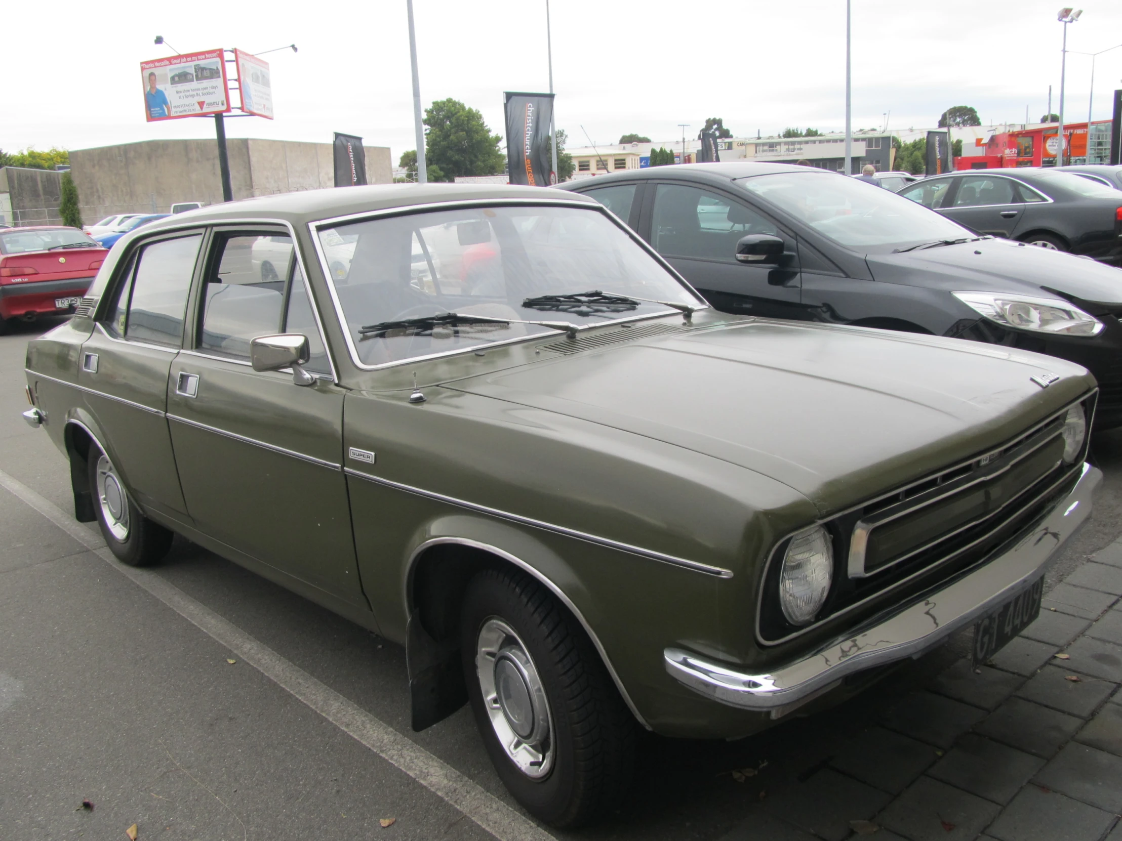 a brown car parked next to other cars on a road