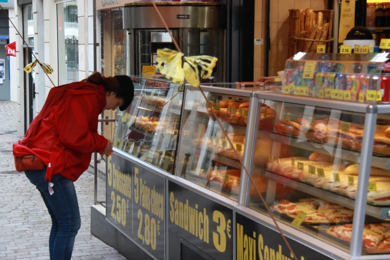 a woman browses through a display window at a bakery
