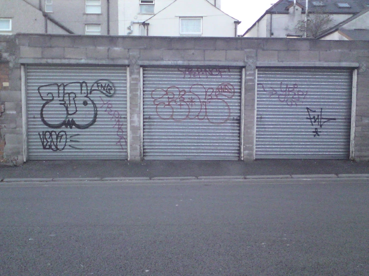 two closed garages on a street with graffiti