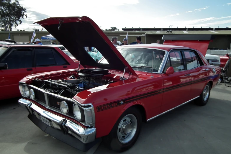 an old model red car with its hood open