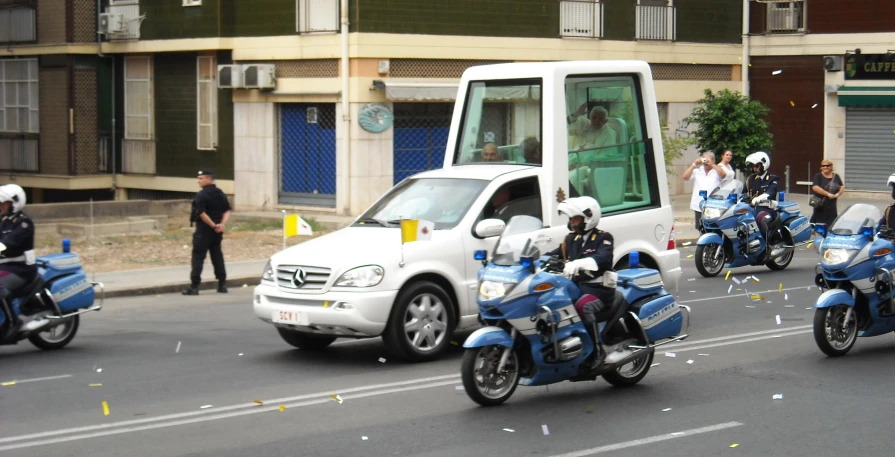 several people in motorcycle helmets riding down the street