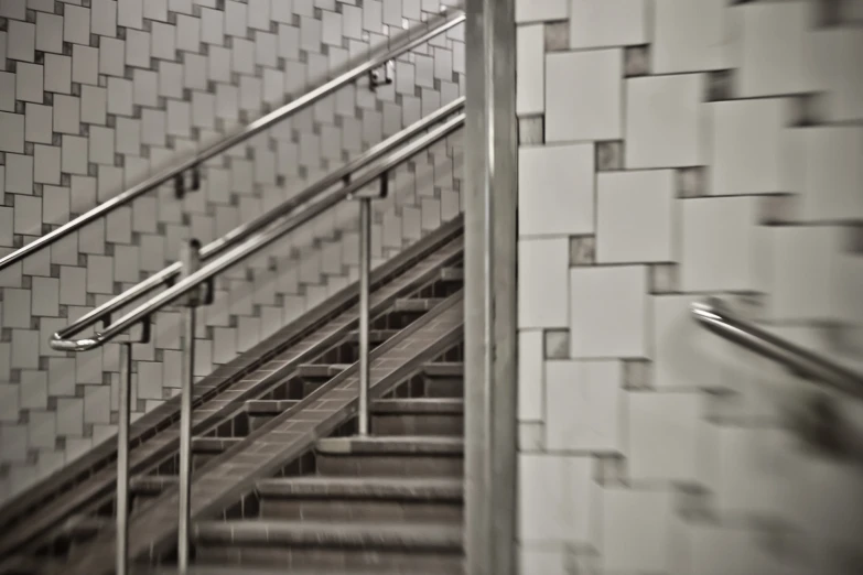 a set of stairs next to tiled walls with a handrail