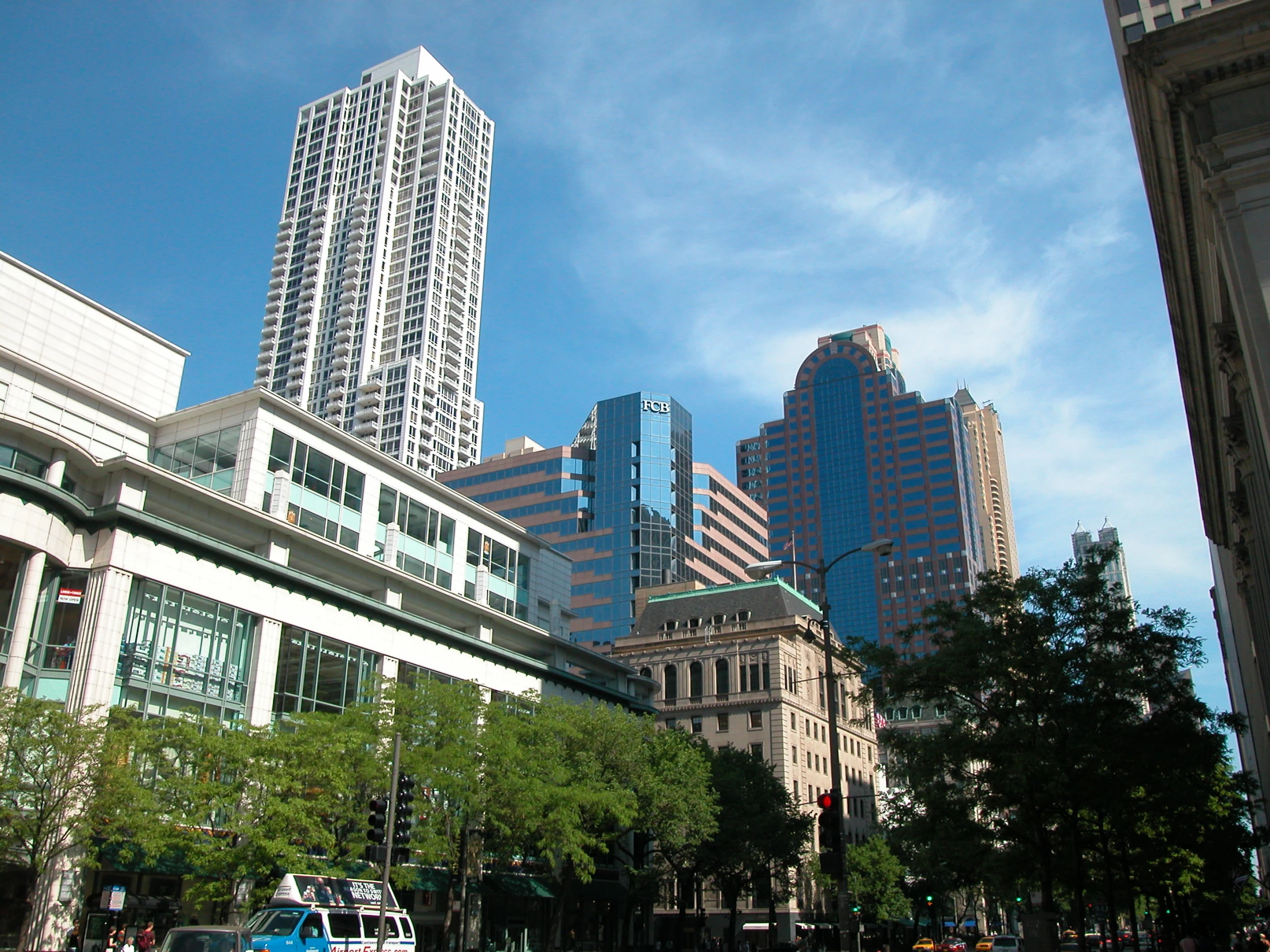 the city with high rise buildings is viewed from the sidewalk