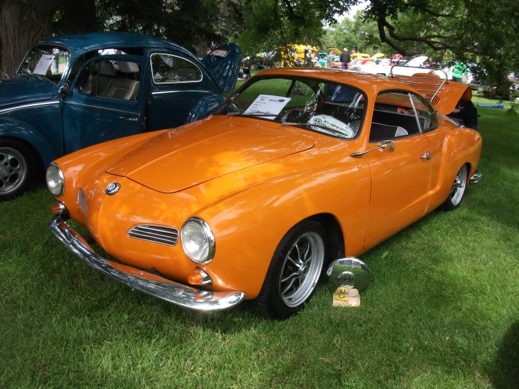 an orange car and a blue car sit in a grassy area