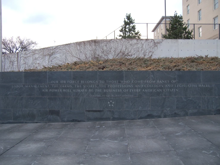 a wall with a plaque next to it on the sidewalk