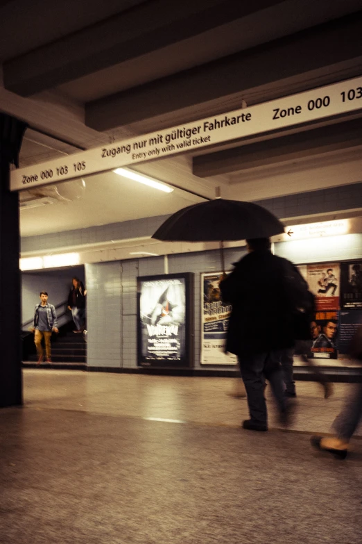 a group of people walking down a hallway carrying an umbrella