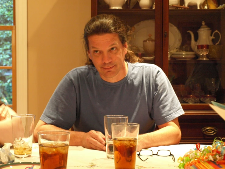 the man is sitting at the table with three glasses on his table