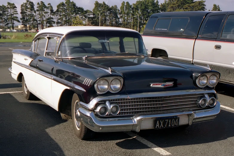 two old cars sitting in a parking lot near each other