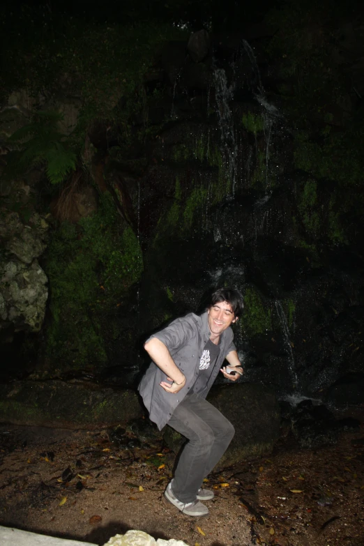 a woman in grey and gray shirt and gray pants near waterfall