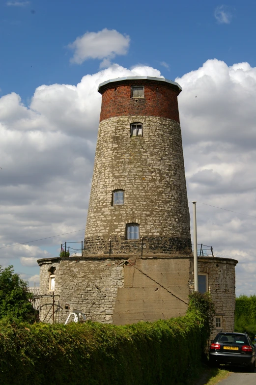 a brick tower near some bushes and a car