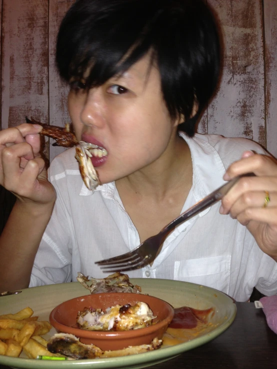 a woman eating an entree in front of some french fries