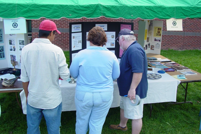 four people stand at a table under a green tent