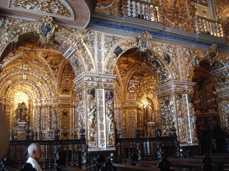 a man looks at an ornate gold alter with intricate carvings