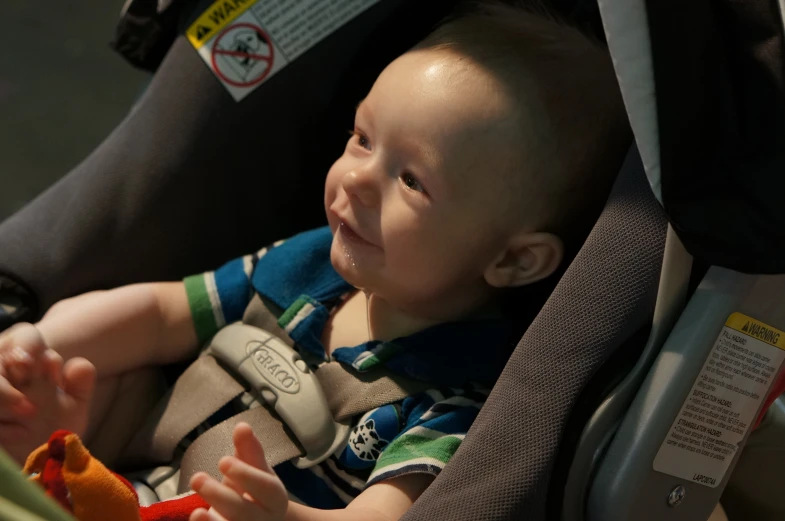 a  sitting in a car seat holding an orange object