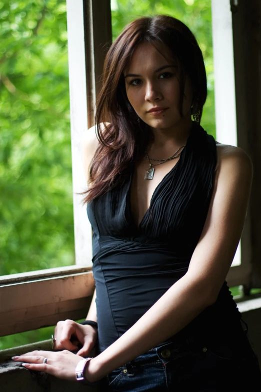 a woman in black is posing by a window