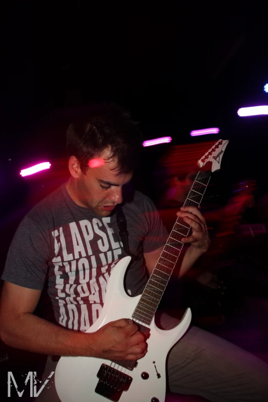a man with an electric guitar stands in a dark room